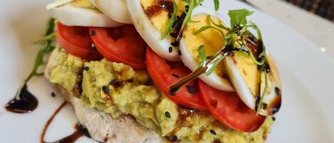 A dish with avocado, tomatoes, and eggs on a white plate.
