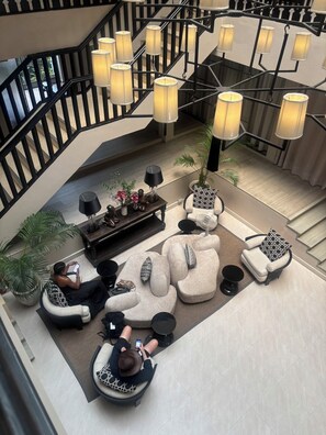 A modern lobby with a staircase, multiple seating areas, and pendant lighting. - The 3 Sis (Chiang Mai)