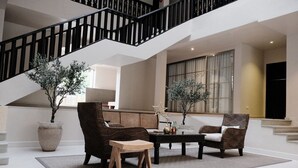 Amplia sala de estar con una escalera moderna, asientos cómodos y grandes ventanales.