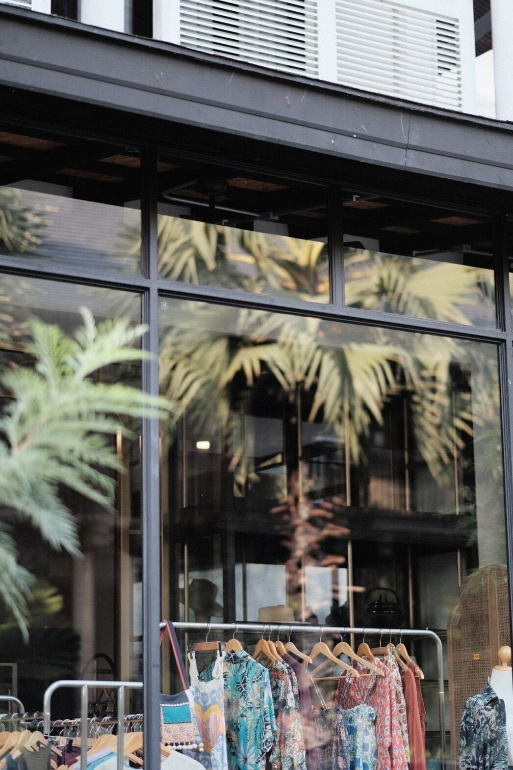 Ein Schaufenster mit einer Kleiderstange vor einem Gebäude mit großen Fenstern.