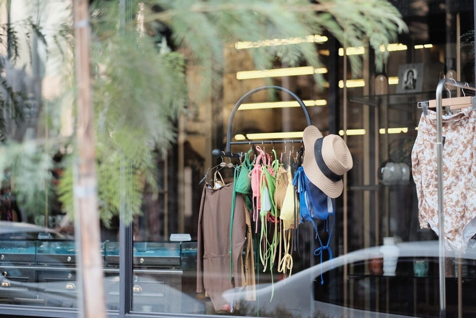A storefront with various clothing items displayed on racks, including hats and dresses.