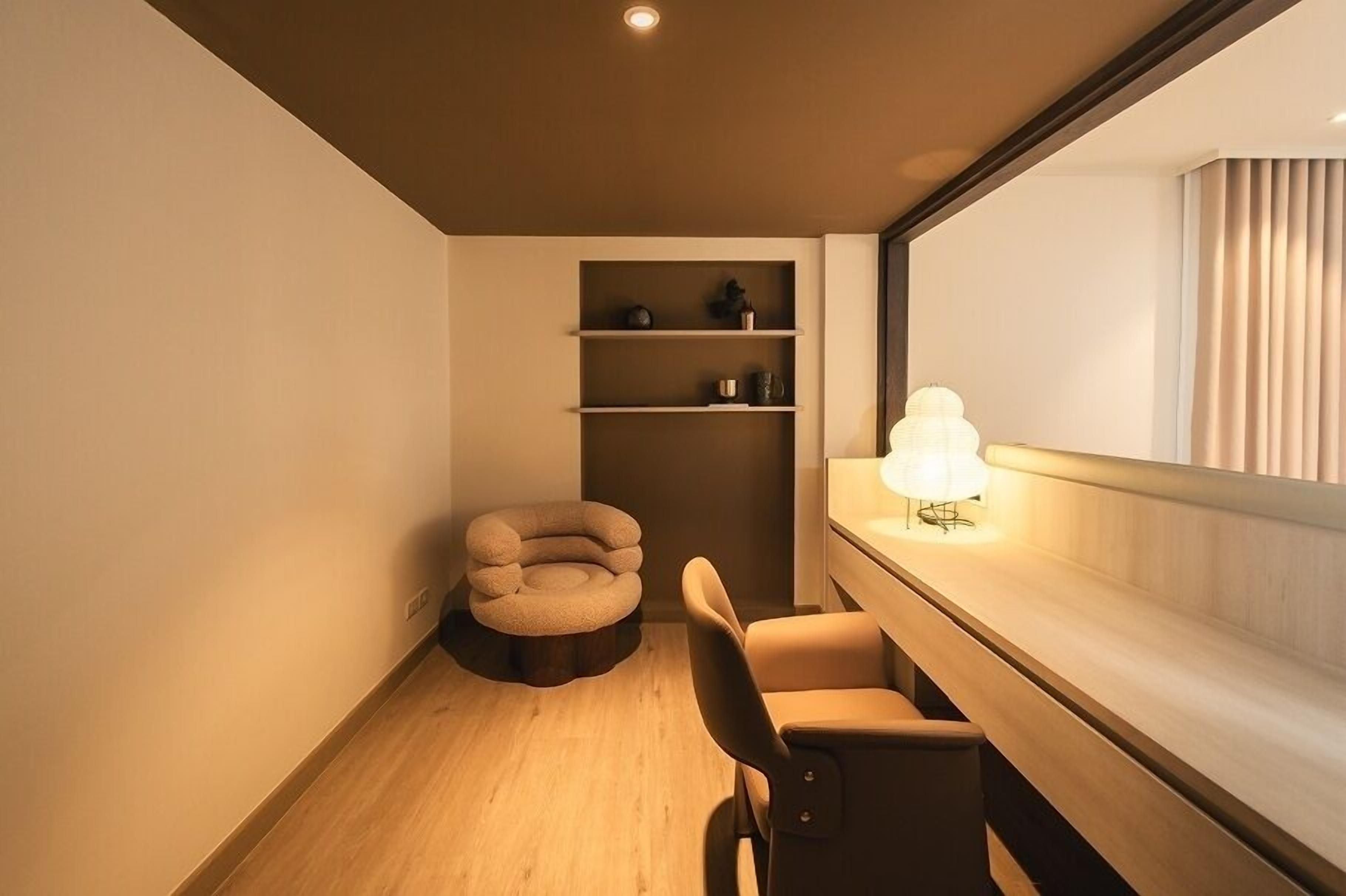 A modern room with a wooden floor, a round chair, a desk with a lamp, and built-in shelves.