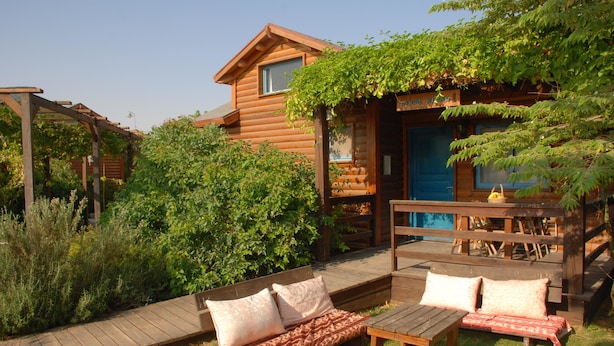 A wooden cabin with a porch, a wooden bench, and a small table.