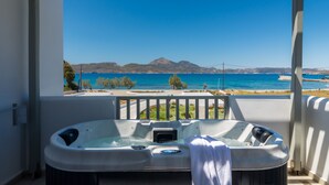 Un jacuzzi con una toalla, con vistas al mar, montañas y un cielo azul despejado.