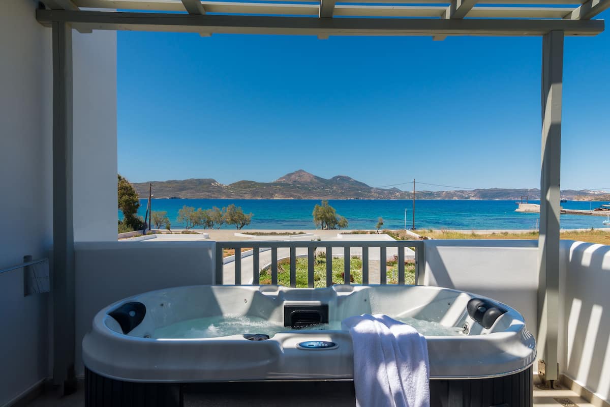 A hot tub with a towel, overlooking a coastal view with mountains and a clear blue sky.