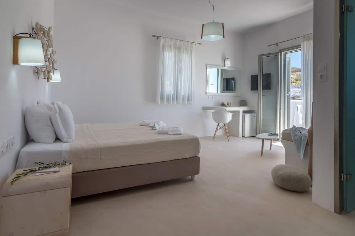 A modern bedroom with a bed, bedside table, and a desk with a chair.