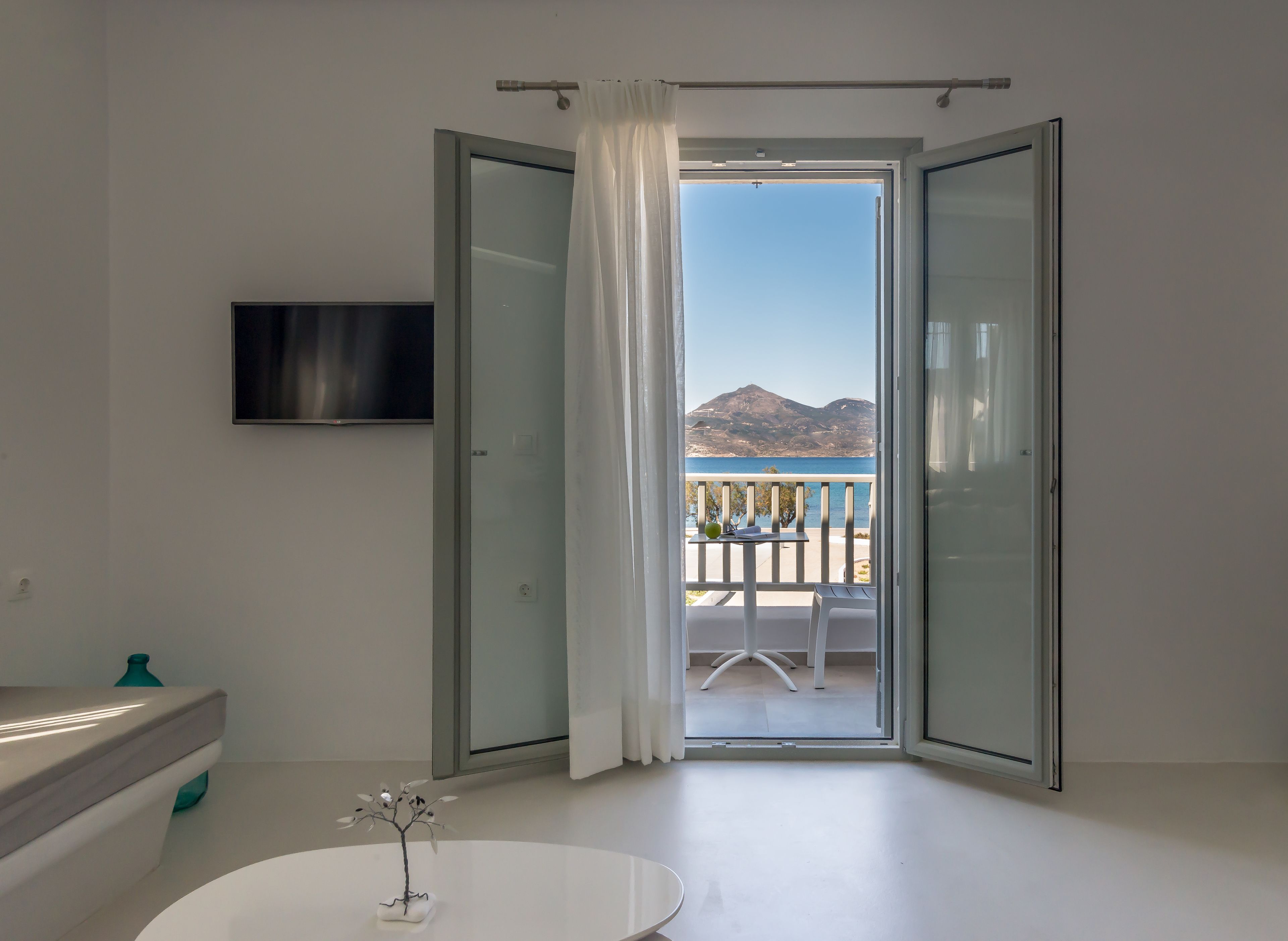 A modern bathroom with a glass door leading to a balcony with a mountain view.