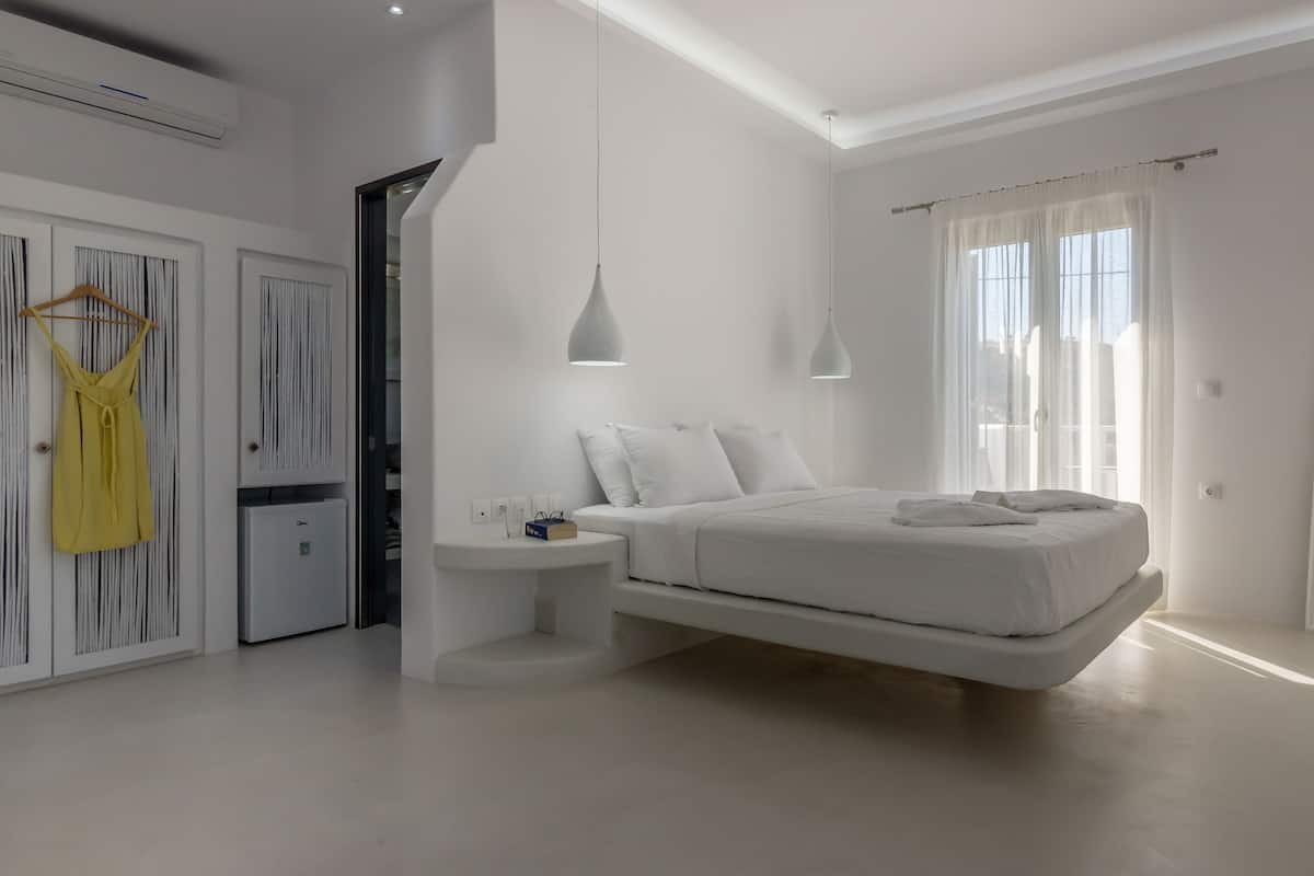 A modern bedroom with a bed, bedside tables, a wardrobe, and a mirror.