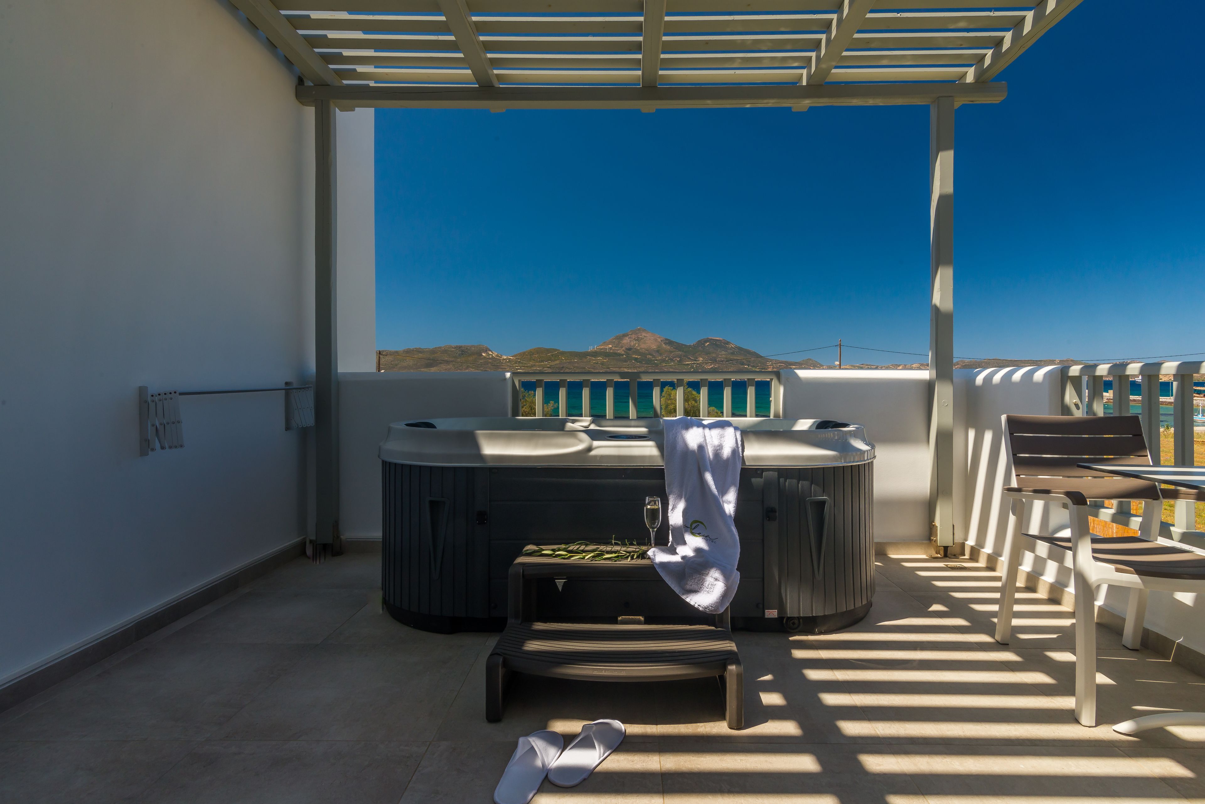 Una terraza en la azotea con jacuzzi, sillas de descanso y vistas al mar.