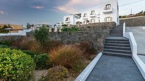 Un edificio moderno blanco con varios balcones, una pared de piedra y una escalera que lleva a los pisos superiores.