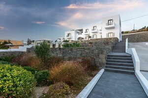 Un edificio moderno blanco con varios balcones, una pared de piedra y una escalera que lleva a los pisos superiores.