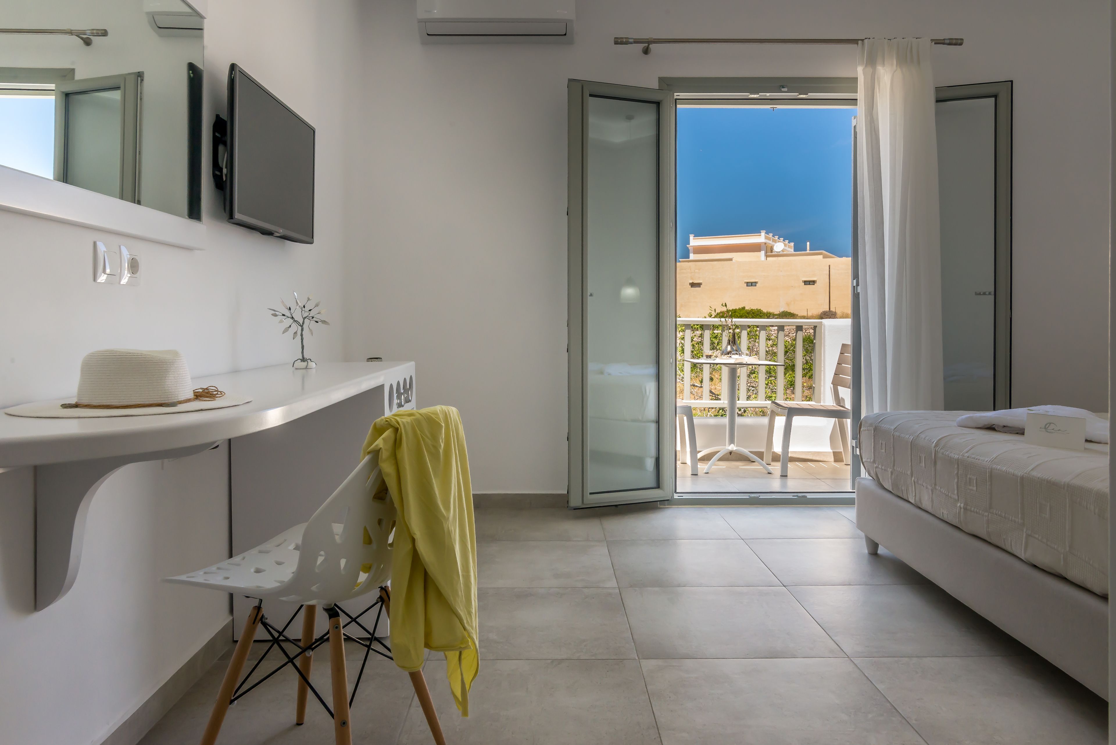 A modern bedroom with a balcony, a white bed, and a small desk area.