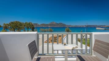 A balcony with a view of the sea, a table with a book, and a chair.