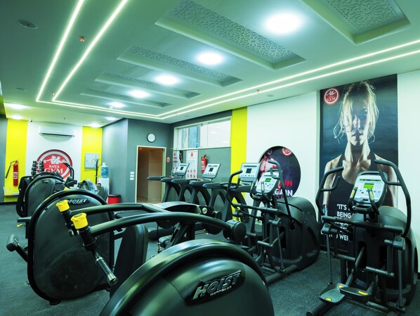 Un gimnasio con cintas de correr, máquinas de pesas y un cartel grande en la pared.