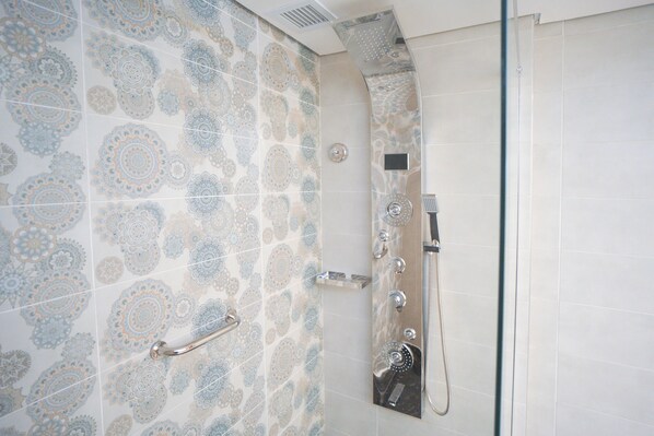 Una ducha con pared de azulejos estampados y puerta de vidrio.