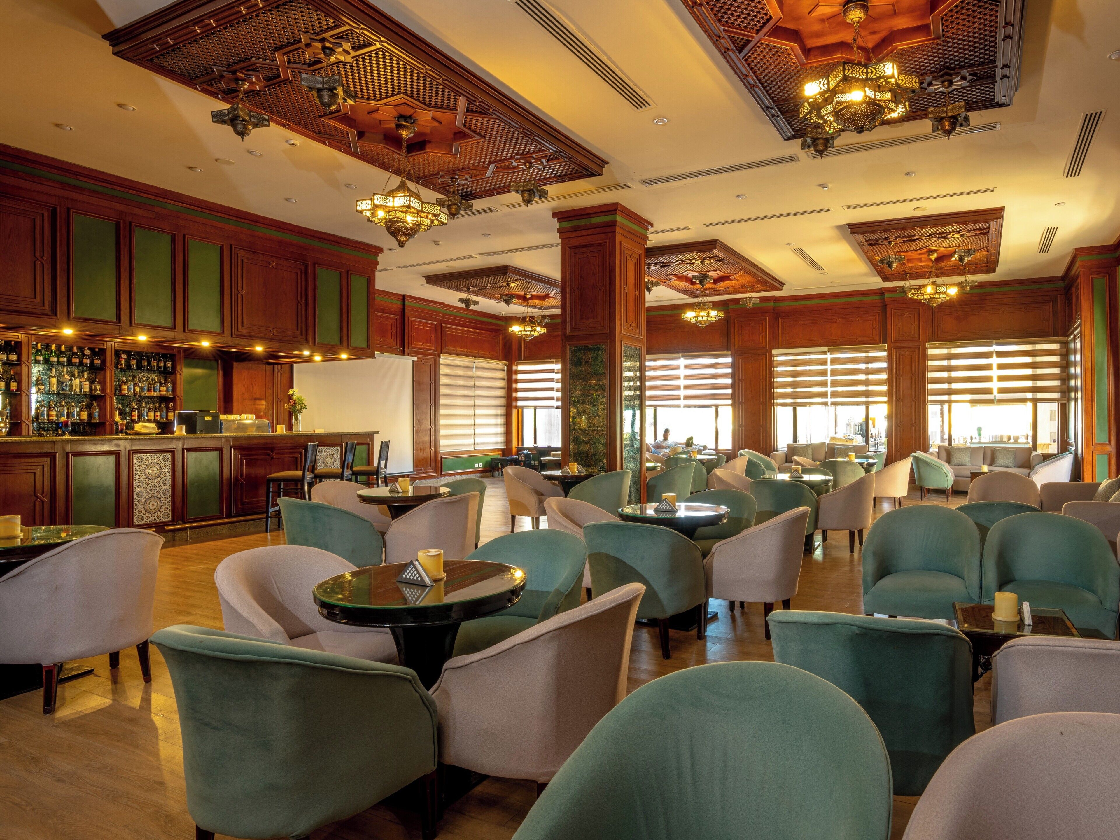 Een ruime lobby met een bar, comfortabele zitplaatsen en decoratieve elementen aan het plafond.