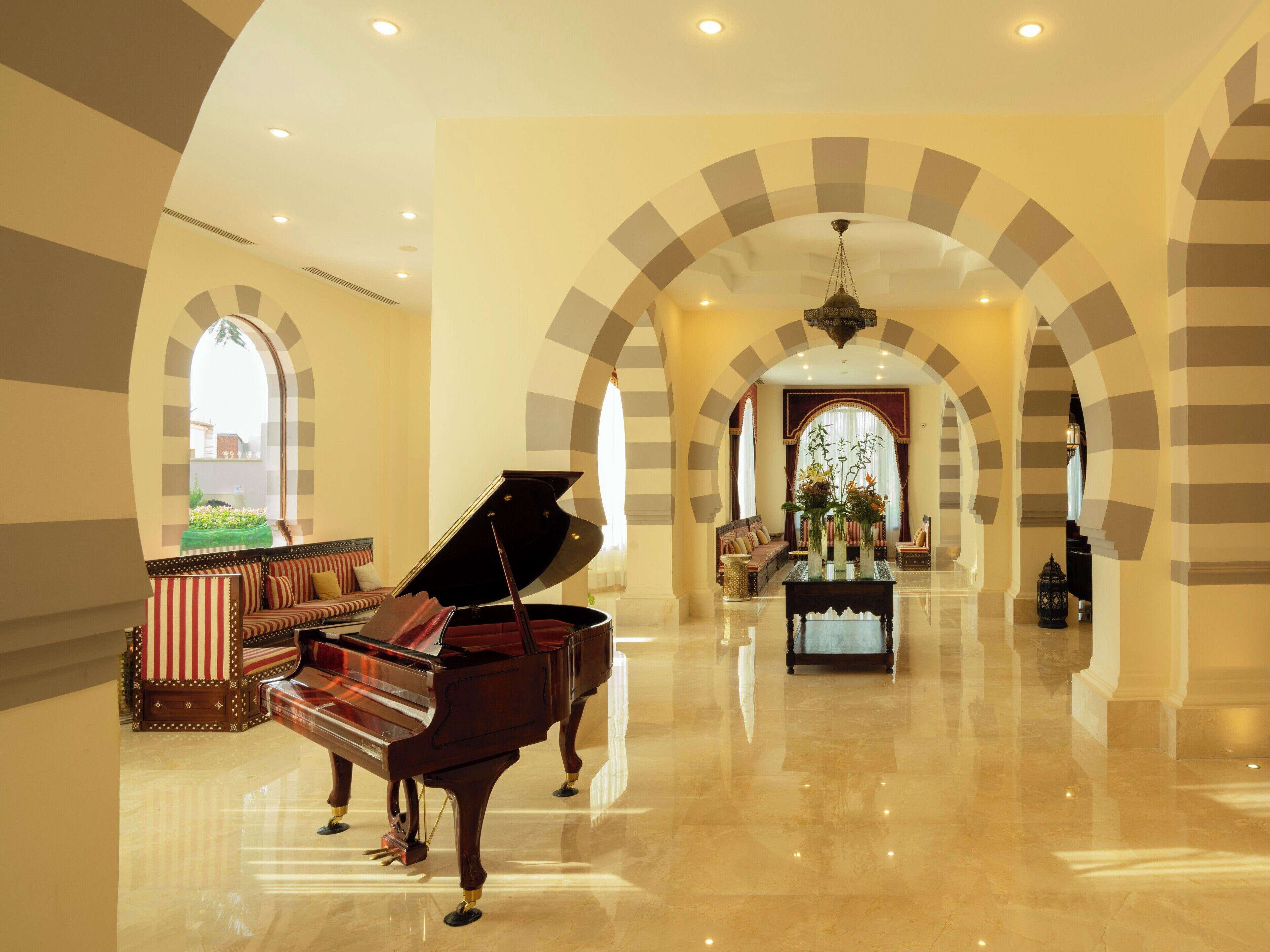 A grand lobby with a grand piano, a sofa, and a decorative table with flowers.
