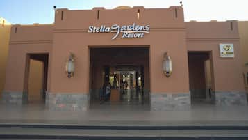 The exterior of Stella Gardens Resort with a clear entrance, stone steps, and two wall-mounted lanterns.