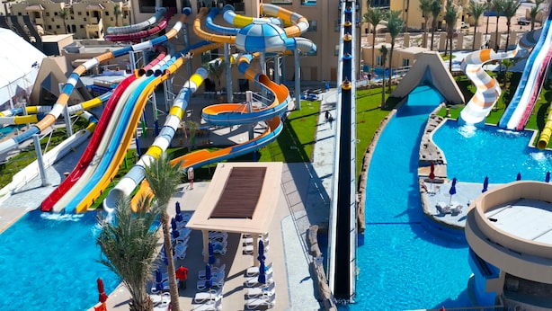 Parque acuático con varias toboganes y piscinas, rodeado de edificios.