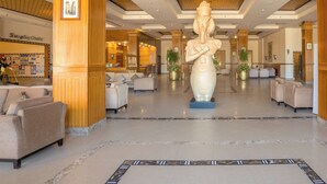 Un vestíbulo amplio con una gran estatua, asientos cómodos y un centro comercial al fondo.