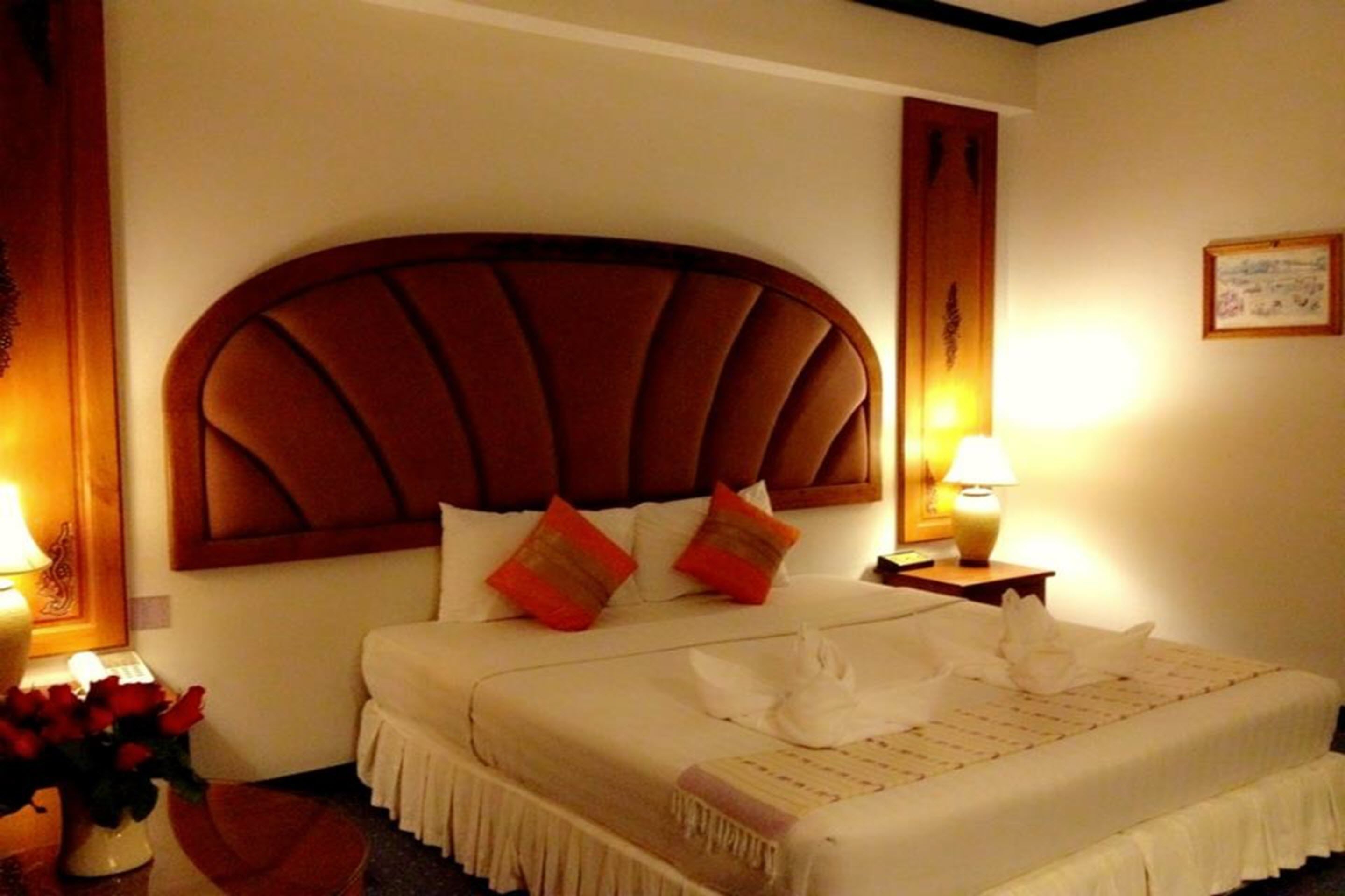 Una habitación de hotel con una cama grande, un cabecero de madera y una mesita de noche con una lámpara.