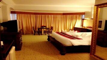 Una habitación de hotel con una cama grande, un escritorio, una silla, un televisor y un espejo.