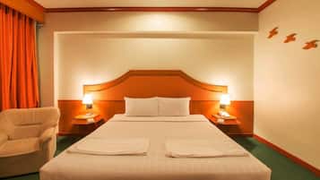 A hotel room with a large bed, two bedside tables with lamps, a chair, and a curtain.