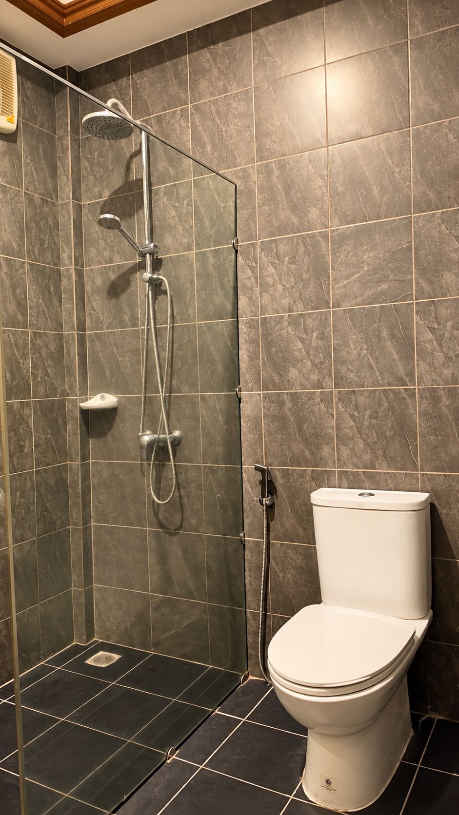 A bathroom with a shower, toilet, and a tiled floor.