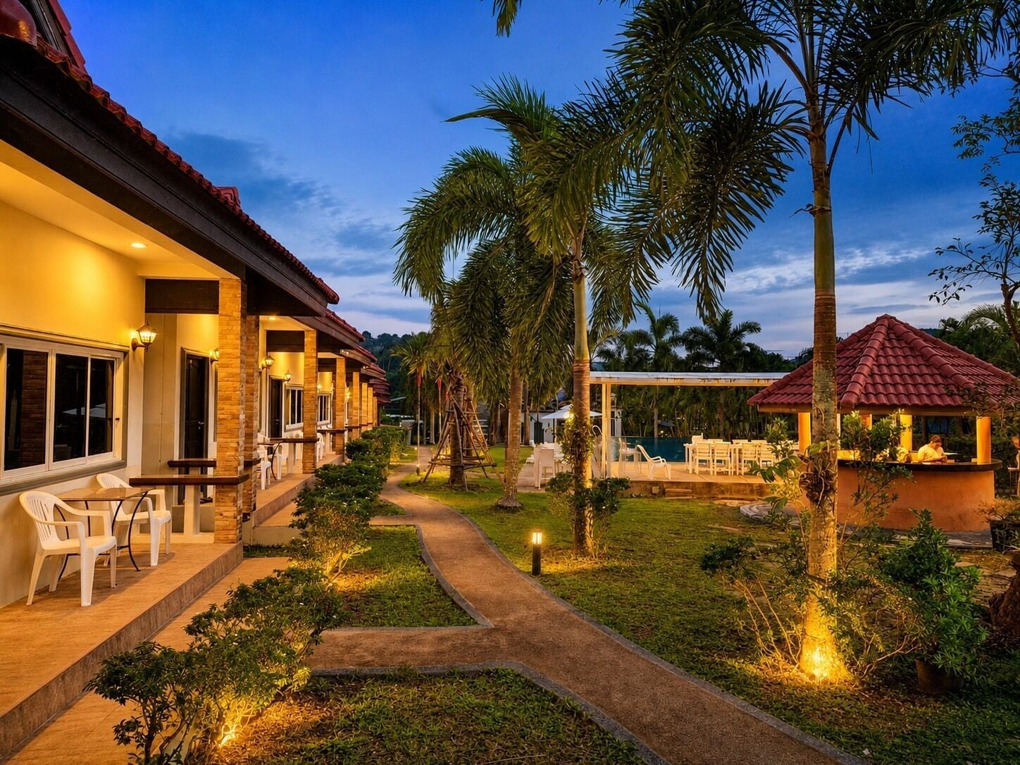 Ein Resort mit Poolbereich, Sitzgelegenheiten im Freien und einem gut beleuchteten Weg.