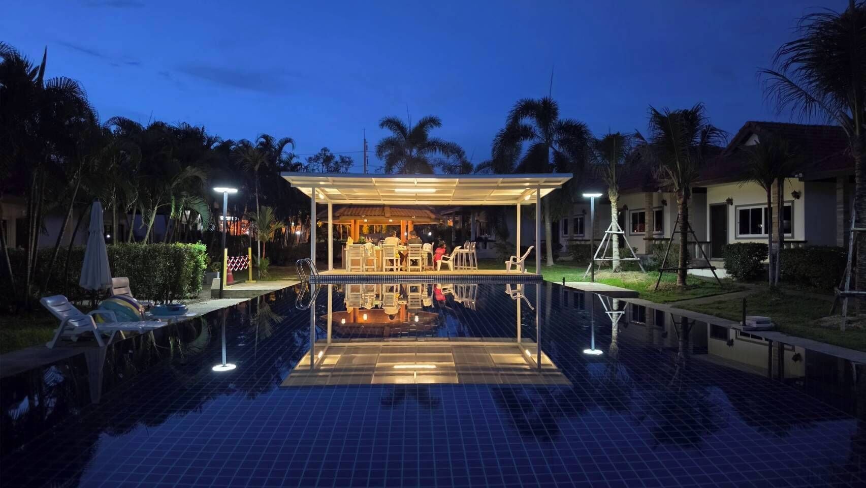 A swimming pool with a covered area and lounge chairs.