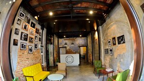 Un espacio lounge acogedor con pared de ladrillo, sofá amarillo, sillas verdes y una mesa blanca.