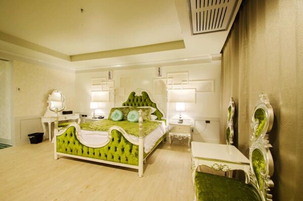 A bedroom with a green upholstered bed, white nightstands, and a mirror with ornate detailing.