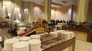 A buffet setup with plates, bowls, and utensils.
