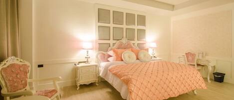 A bedroom with a large bed, two bedside tables, a chair, and a desk.