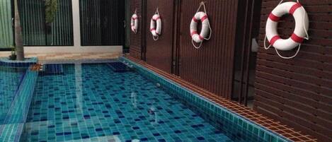 A swimming pool with blue tiles and life rings on the wall.