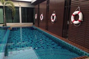 A swimming pool with blue tiles and life rings on the wall.