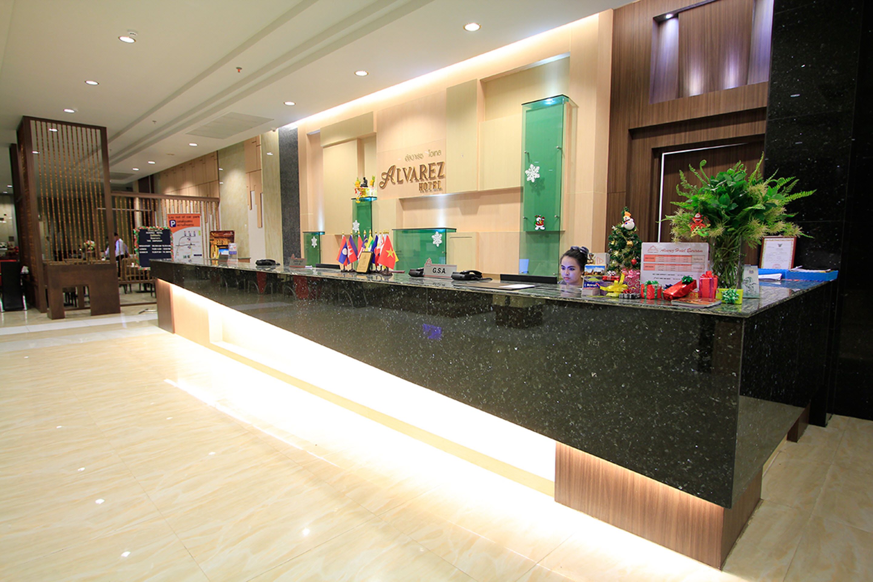 A hotel reception desk with a modern design, a sign for the Alvarez Hotel, and a Christmas tree decoration.