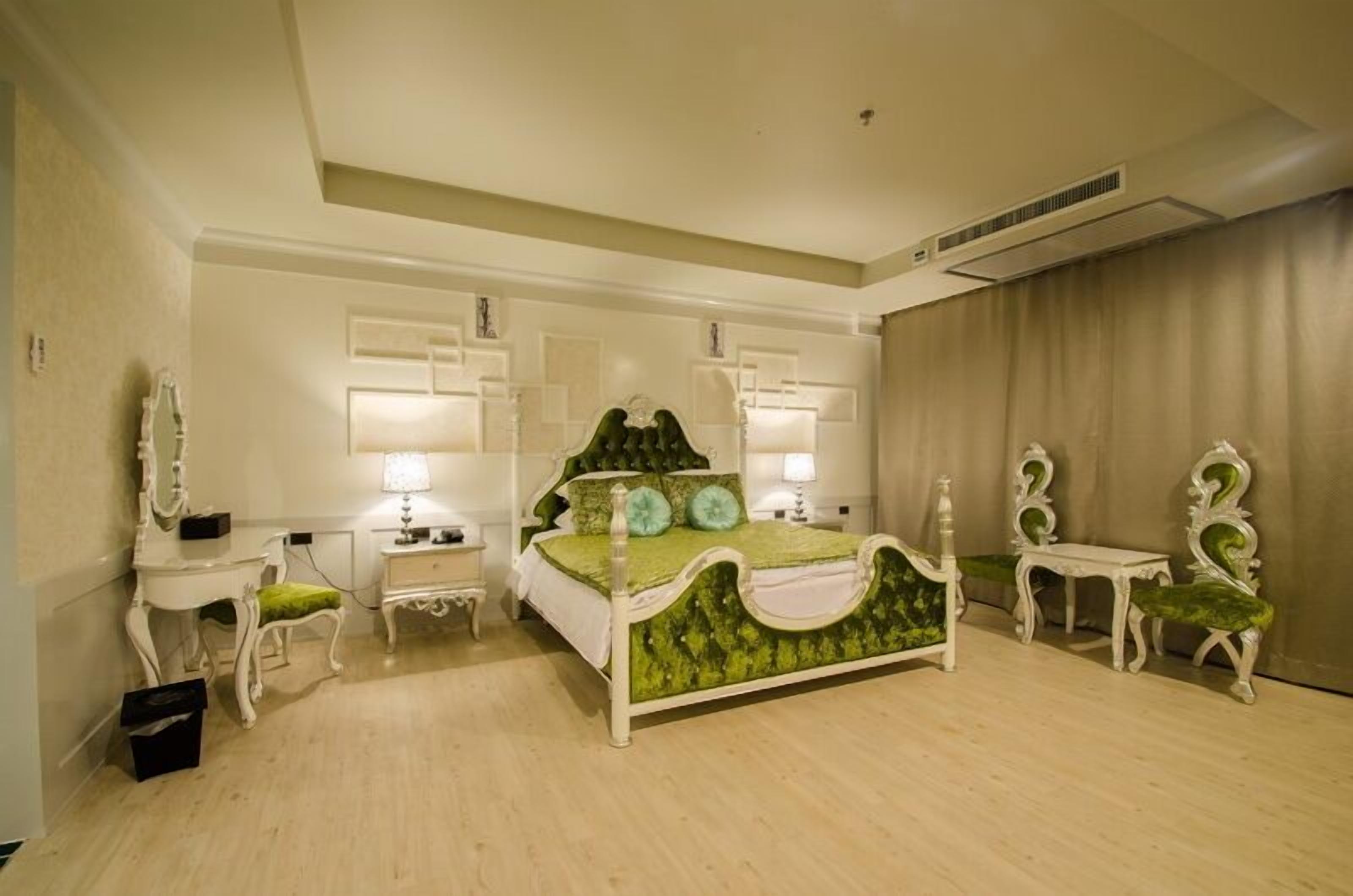 Un dormitorio con cama con dosel, dos mesitas de noche, un tocador y dos sillas.
