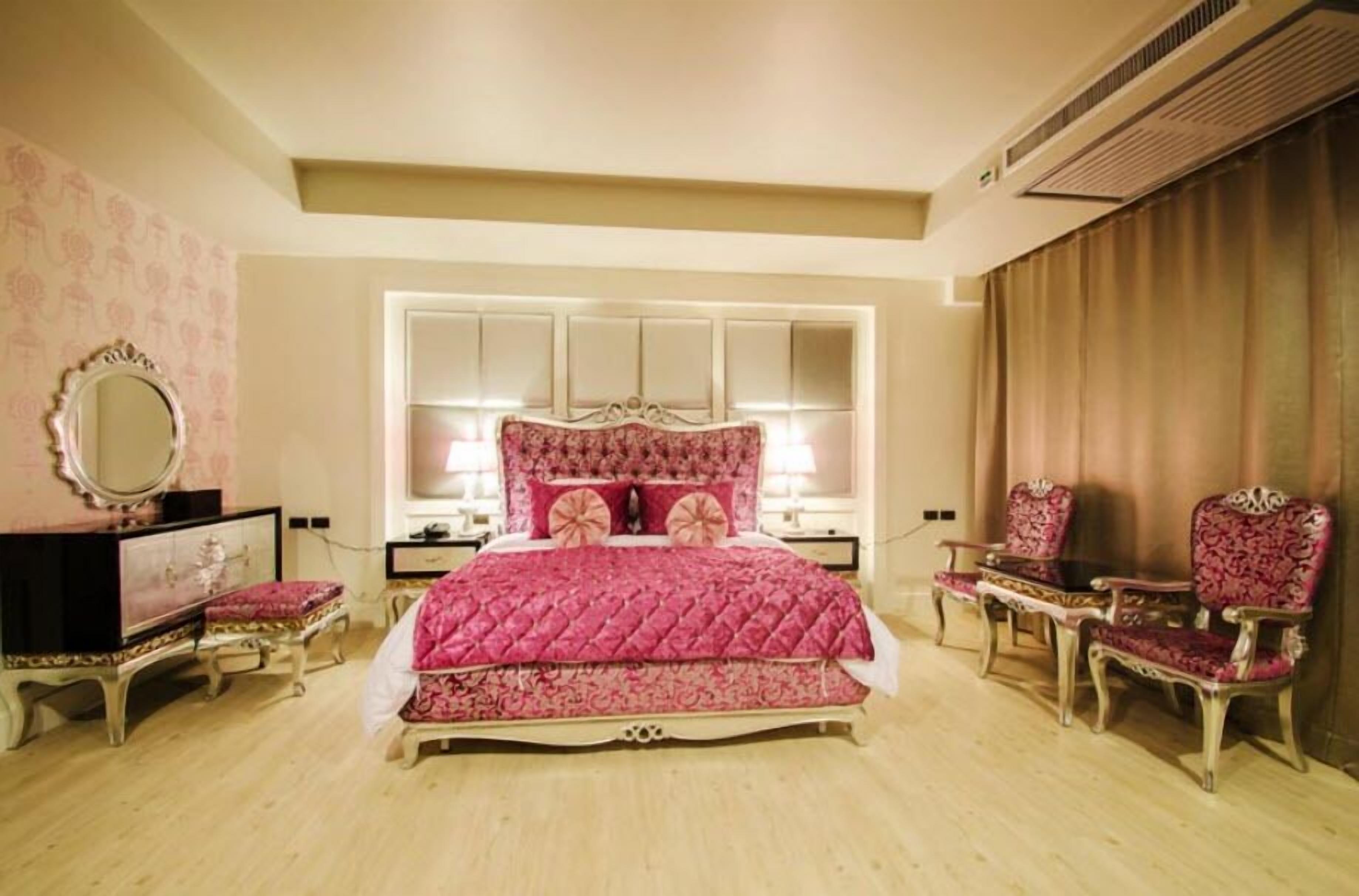 Een slaapkamer met een groot bed, een dressoir, een kaptafel en twee stoelen.