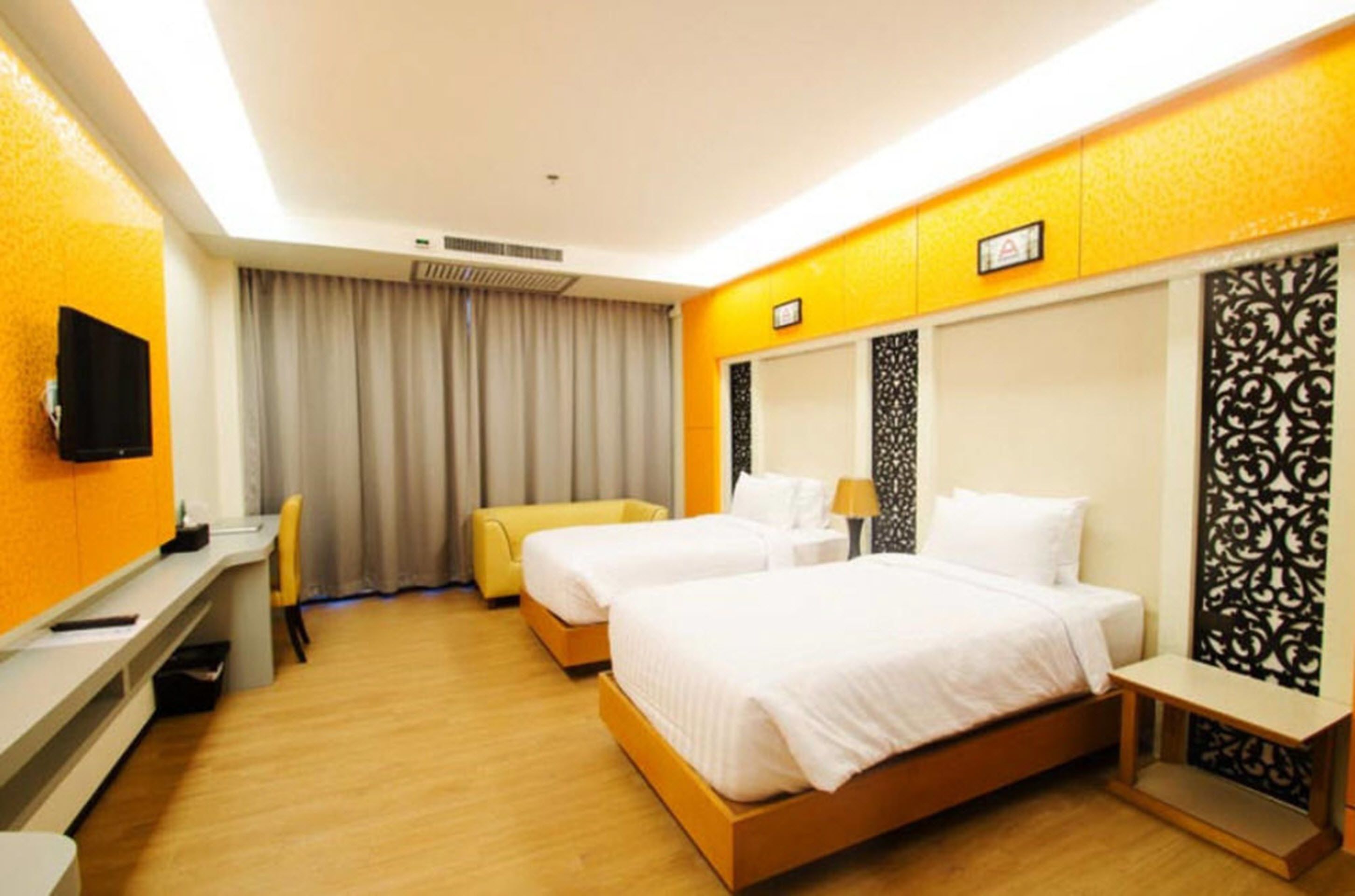 A hotel room with two beds, a desk, a chair, a TV, and a curtain.