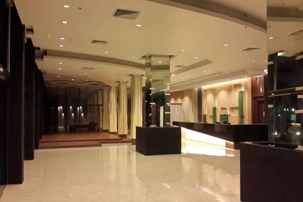 Un vestíbulo amplio con diseño moderno, que incluye un mostrador de recepción, un área de descanso y una vista despejada del pasillo que conduce a otras partes del hotel.