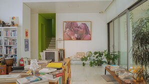 A library with bookshelves, a large painting, and potted plants. - Motif No.1 Guest House (Paju)