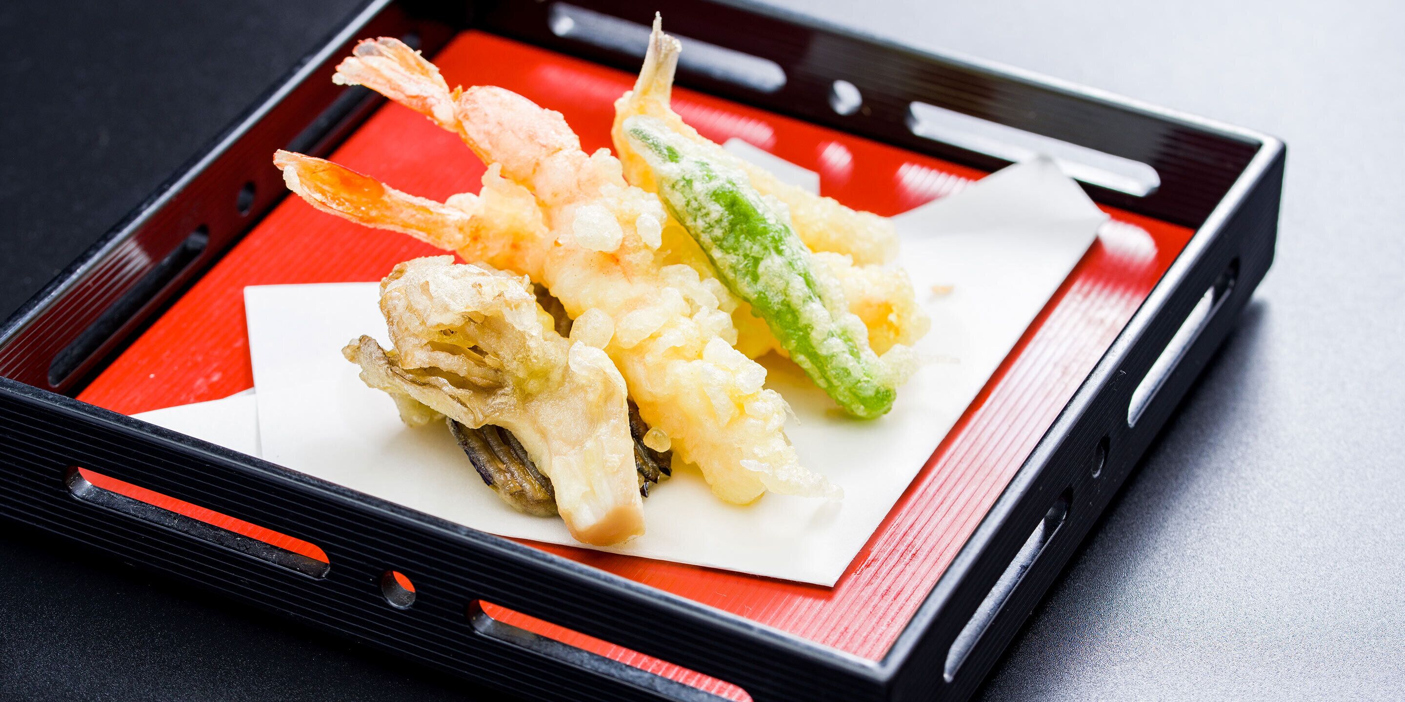 A tray with tempura shrimp and vegetables on a white plate.