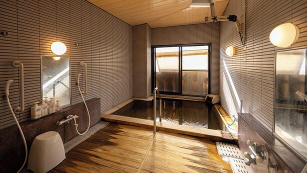 Un baño moderno con suelo de madera, una bañera grande y una ventana que proporciona luz natural.