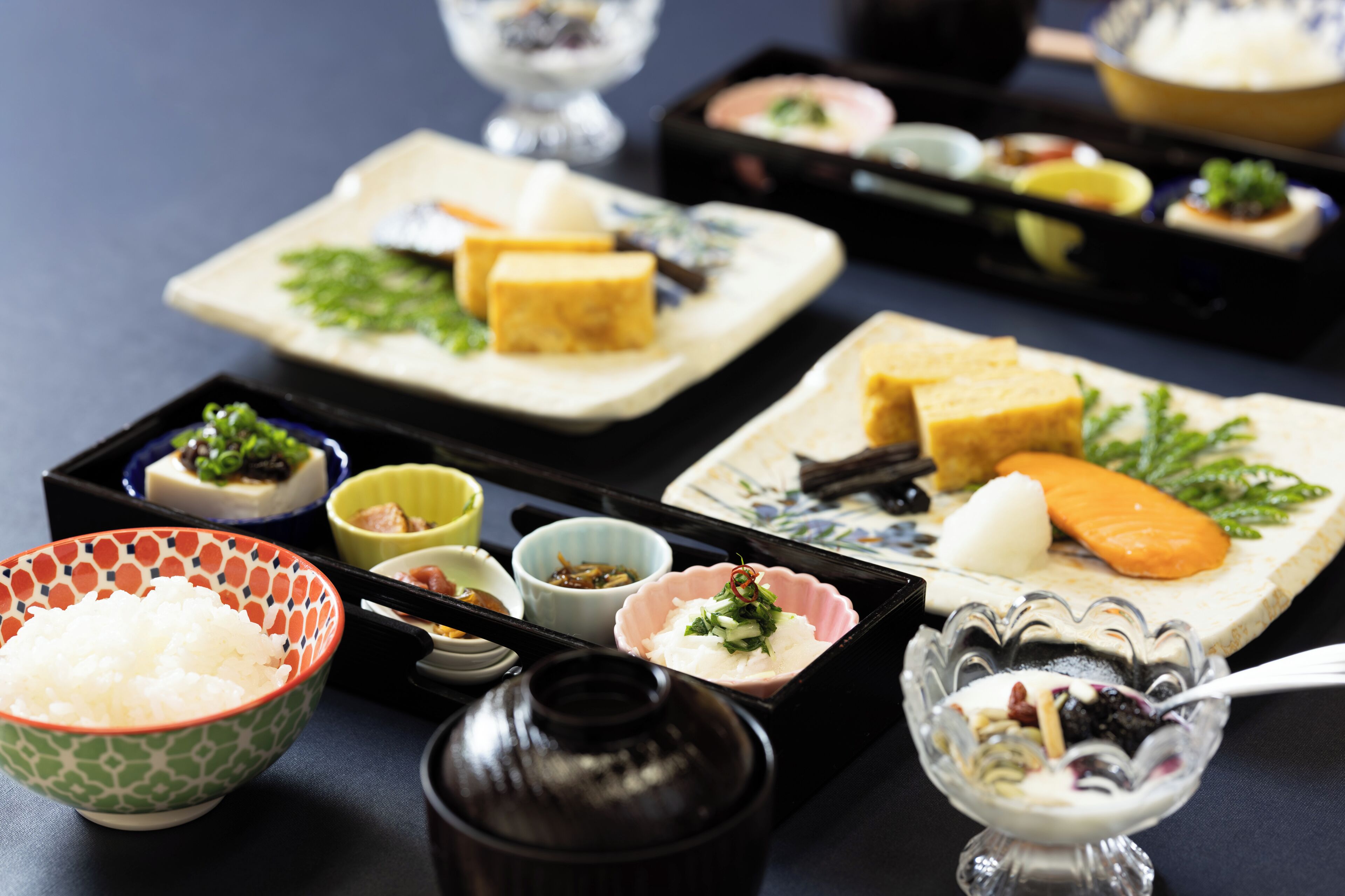 Diversos platos de comida japonesa sobre bandejas negras.