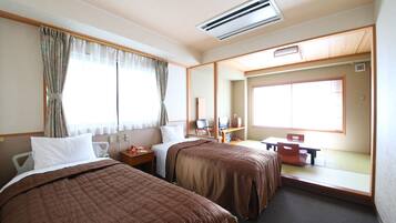 A hotel room with two beds, a desk, a chair, a small table, and a large window with curtains.