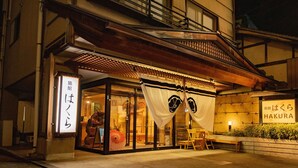 Un edificio japonés tradicional con fachada de madera, amplias puertas correderas y un letrero que dice 
