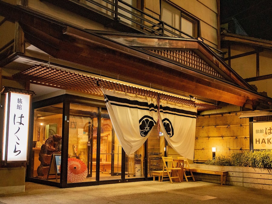 Un edificio japonés tradicional con fachada de madera, amplias puertas correderas y un letrero que dice