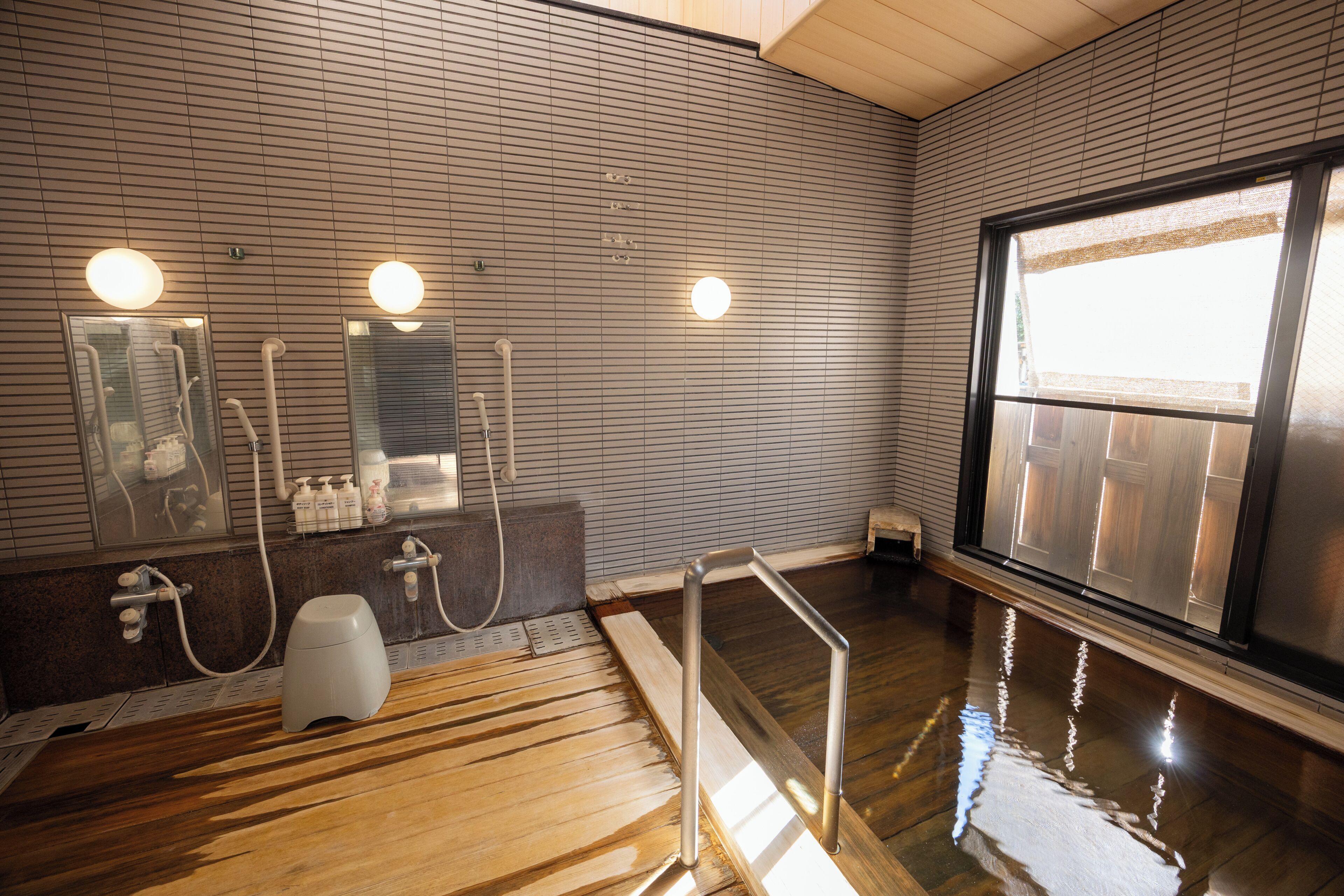 Un bagno moderno con pavimento in legno, uno specchio grande e una finestra.