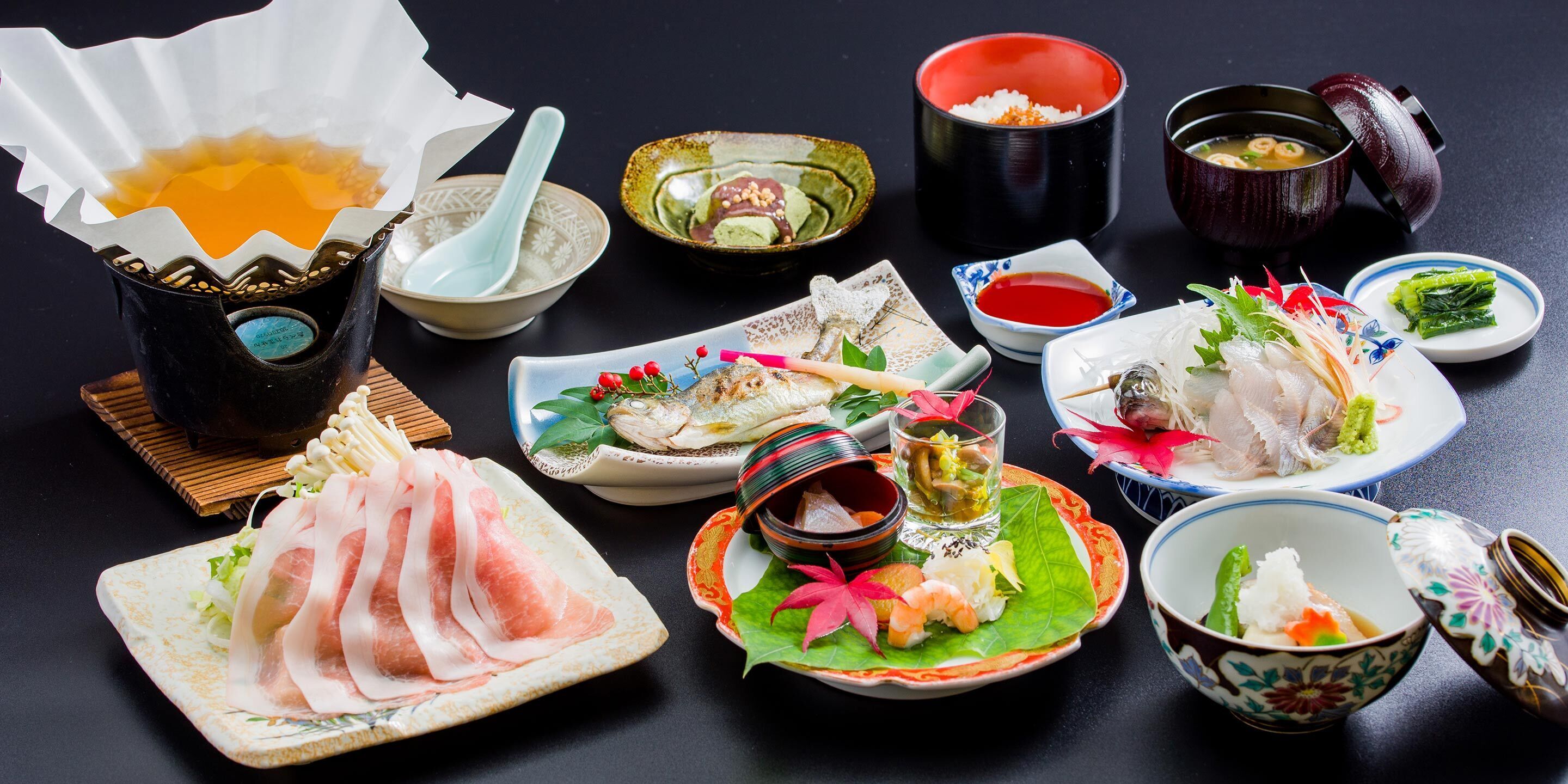 A variety of Japanese dishes including sashimi, sushi, and a hot pot setup.